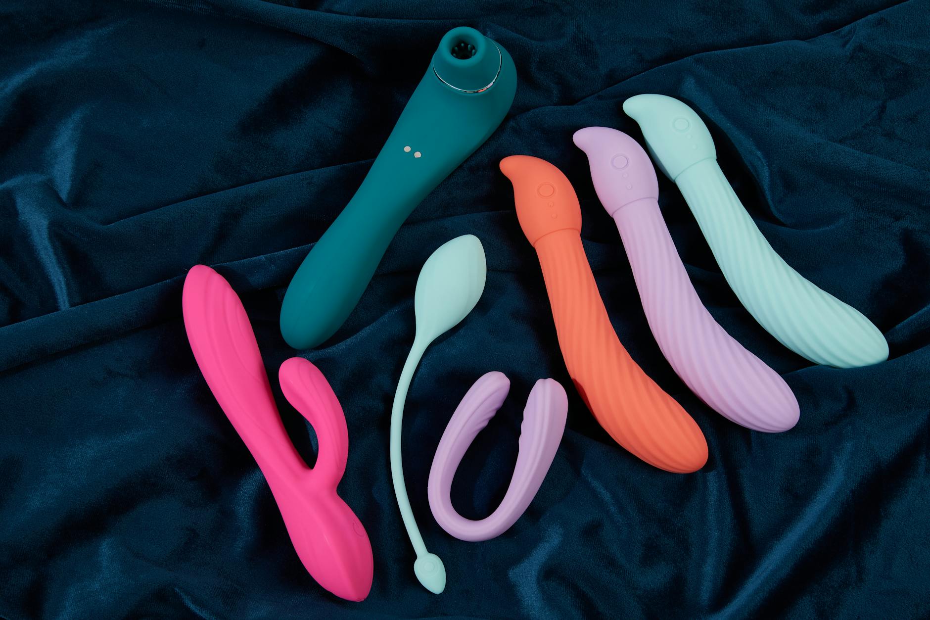 Silicone clitoral vibrators in various colors displayed on dark fabric