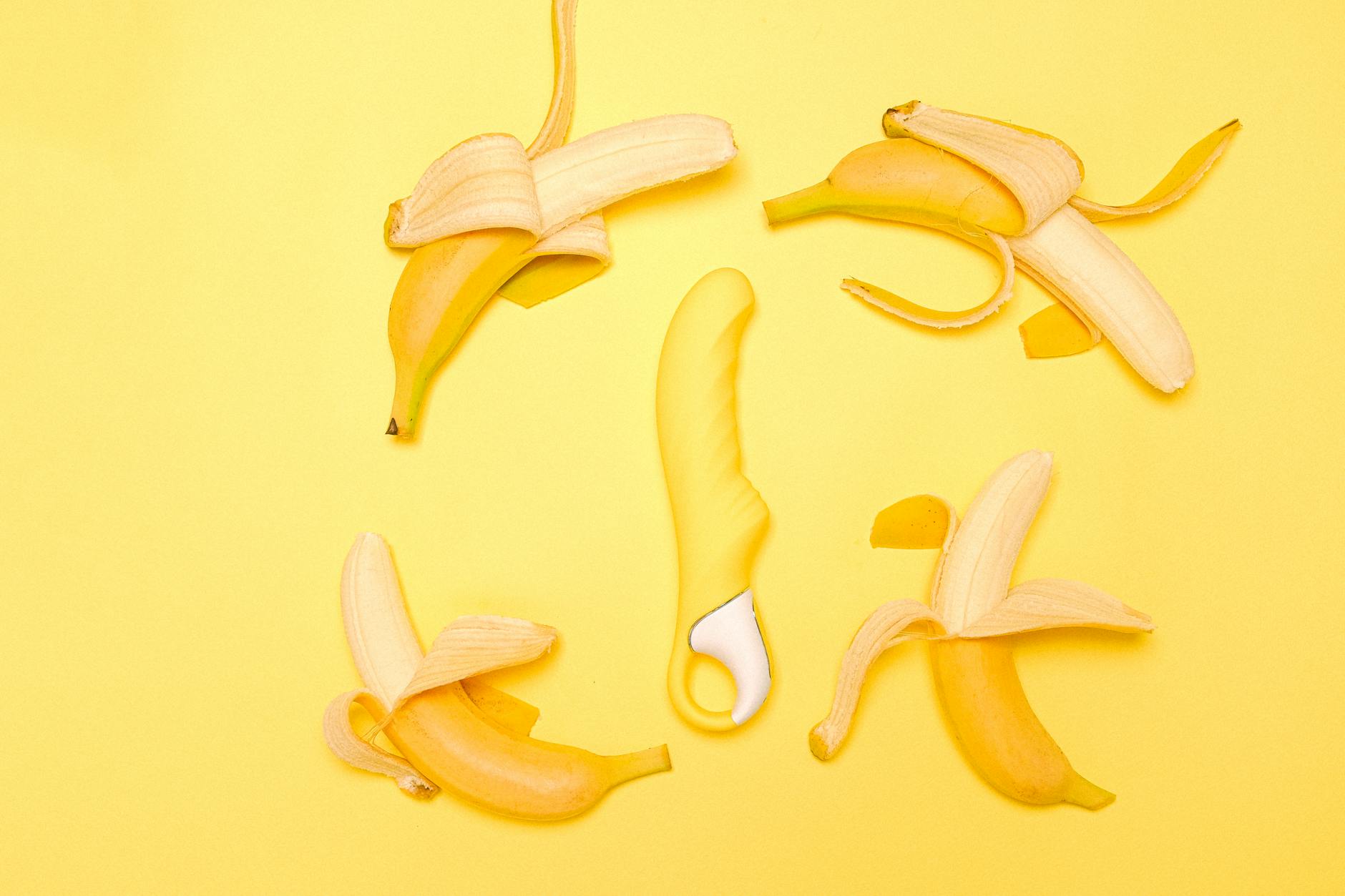A bright yellow silicone lemon vibrator on a pastel yellow background