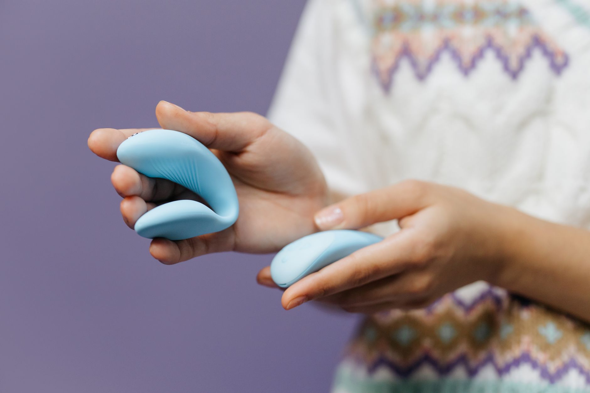 Close-up of hands exploring a lemon vibrator together in intimate light.