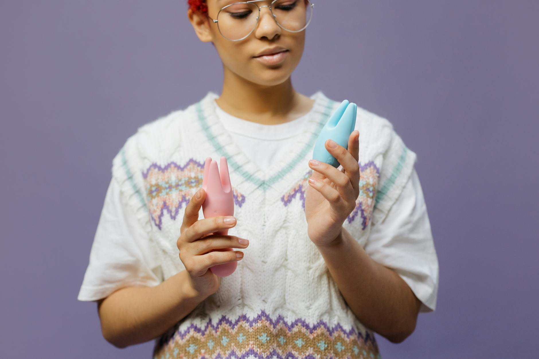 Woman holding a vibrator in a thoughtful, reflective pose with soft lighting