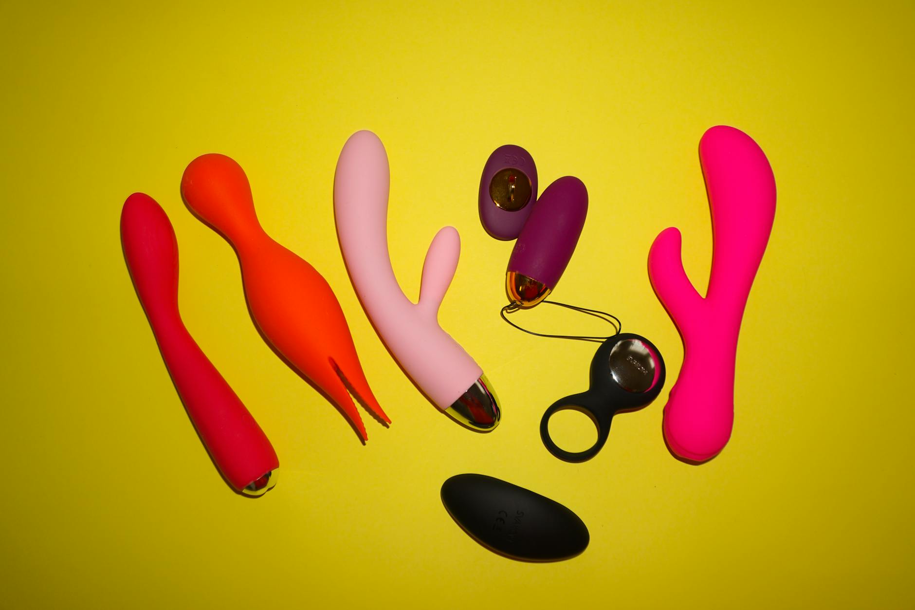 Colorful collection of modern clitoral vibrators displayed on a bright yellow background